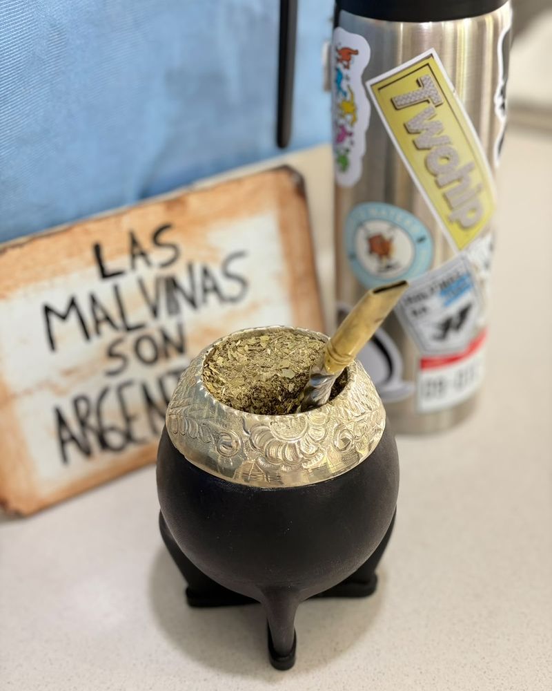 Mate torpedo negro con virola cincelada frente a un cartel que dice Las Malvinas son argentinas